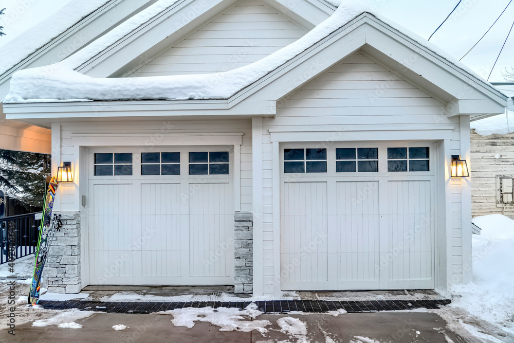 Home exterior with white walls gabled roofs and two glass paned garage