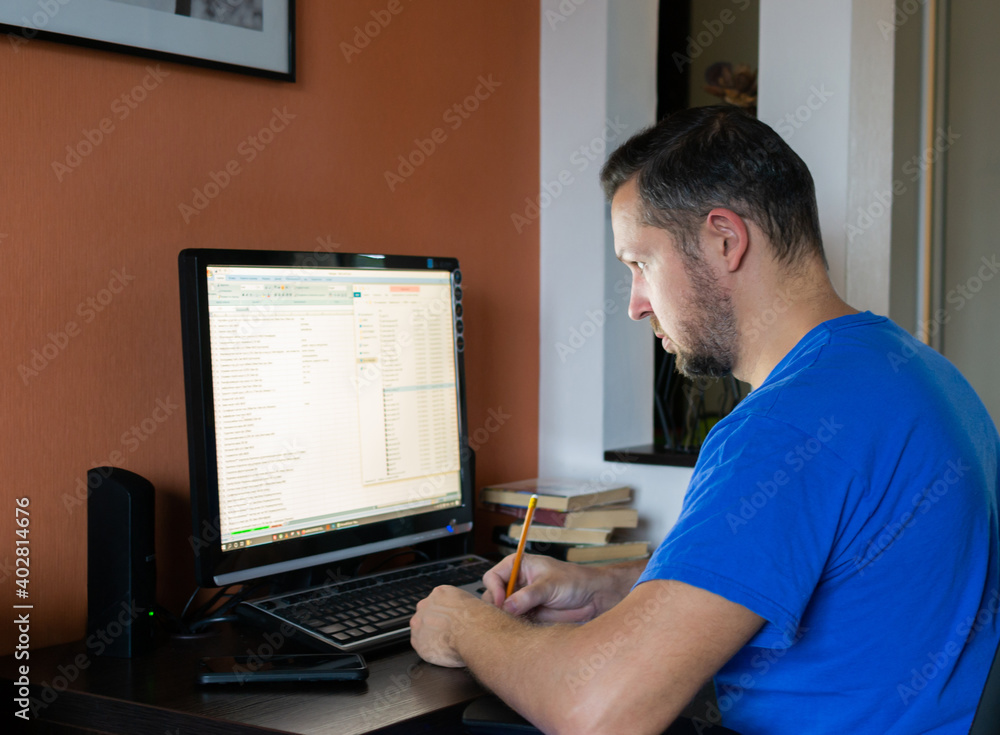 Young man works on the computer online at home. Programmer freelance work. Young man works on the computer online at home. Programmer freelance work.