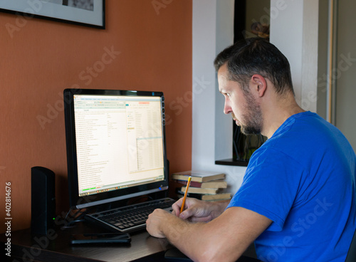 Young man works on the computer online at home. Programmer freelance work.