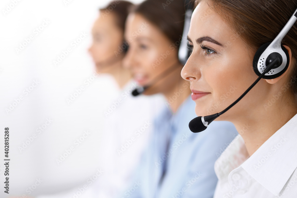 Call center. Group of operators at work. Focus on beautiful business woman in headset Call center. Group of operators at work. Focus on beautiful business woman in headset