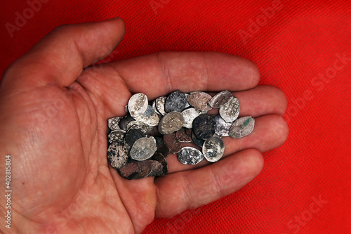 Medieval russian silver coins on the palm on red background photo