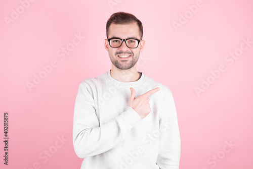 Portrait of a young man with a smile points his index finger towards copyspace © MP Studio