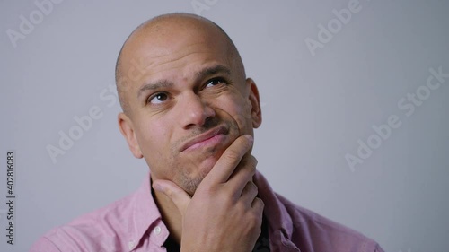 Young man looking to camera wondering about something before looking confidently to camera and smiling, in slow motion