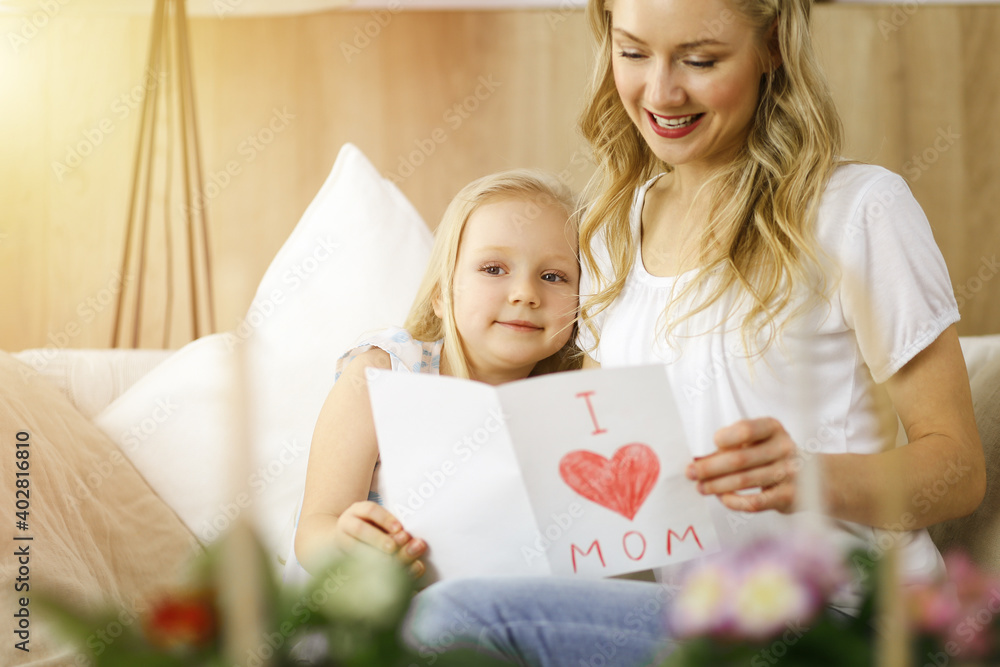 Happy mother day in sunny flat. Child daughter congratulates mom and gives her postcard with heart drawing. Family concept Happy mother day in sunny flat. Child daughter congratulates mom and gives her postcard with heart drawing. Family concept
