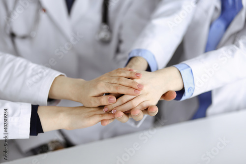 Group of modern doctors joining hands as a circle and ready to help patients. Teamwork in medicine during Coronavirus pandemic. Covid 2019 © rogerphoto
