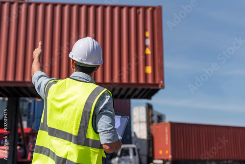 Logistics engineer working with computer notebook and looking Shipping containerin commercial transport port