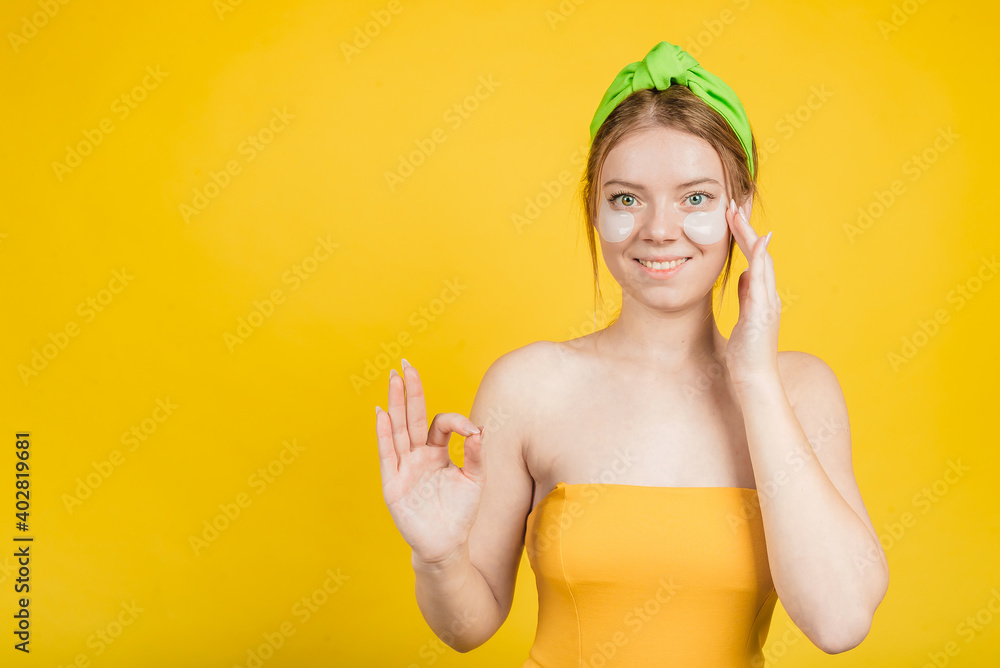 young girl with patch under eyes isolated on yellow background young girl with patch under eyes isolated on yellow background