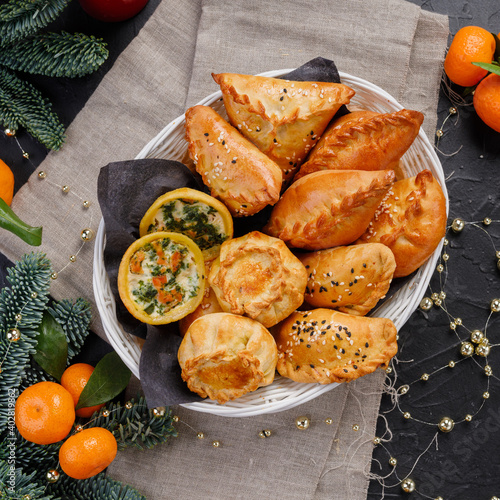 different types of small pies in a basket on a dark background. Bakery products. Catering. Delivery
