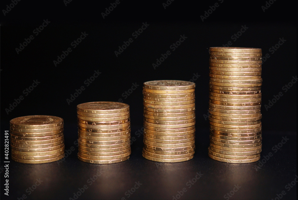 Increasing columns of coins on table, black background.