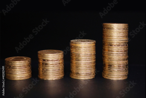 Obraz na płótnie Increasing columns of coins on table, black background. w salonie