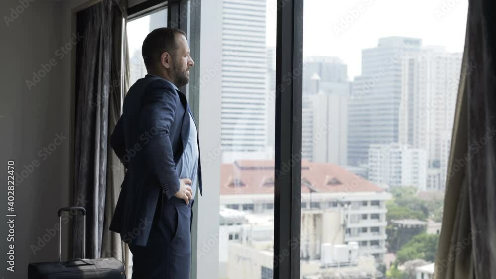 Businessman admire city view standing by window at hotel Businessman admire city view standing by window at hotel