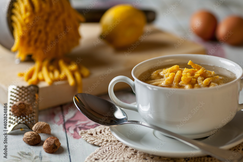 Passatelli in chicken broth with ingredients on the background Passatelli in chicken broth with ingredients on the background
