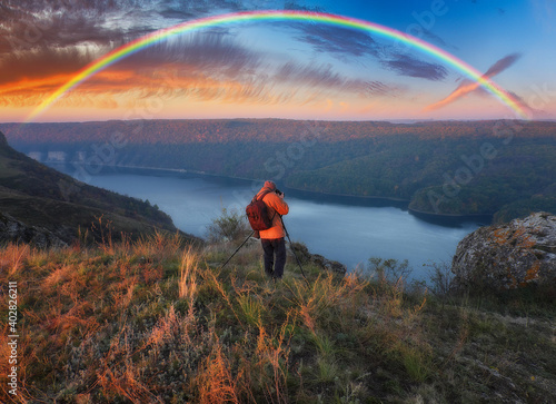 rainbow over the river. man on a cliff above the canyon