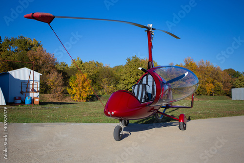 Red autogyro parked at the airfield in sunny day. Gyrocopter against the blue sky. photo
