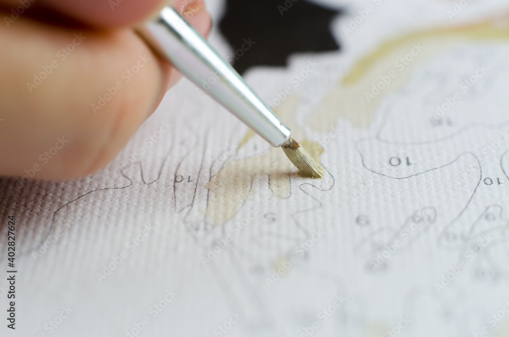 Woman paints on canvas. Woman's hand holding a brush for drawing close-up Woman paints on canvas. Woman's hand holding a brush for drawing close-up