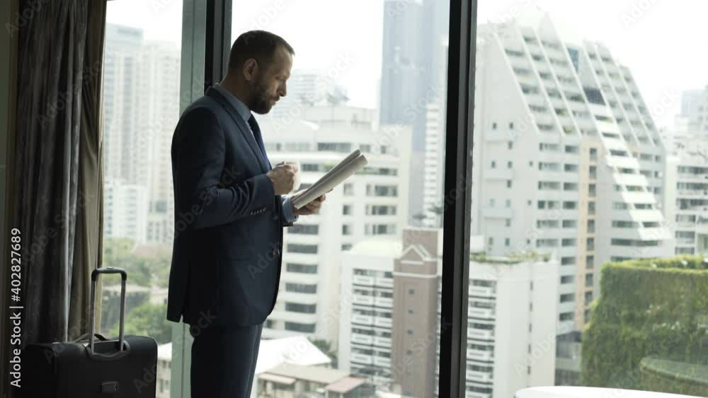 Young businessman reading magazine and drinking coffee by the window Young businessman reading magazine and drinking coffee by the window