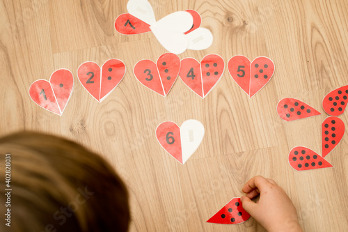 counting hearth shape game. dots and numbers. find a pair. wood background. kid playing on the floor. mathematic task.