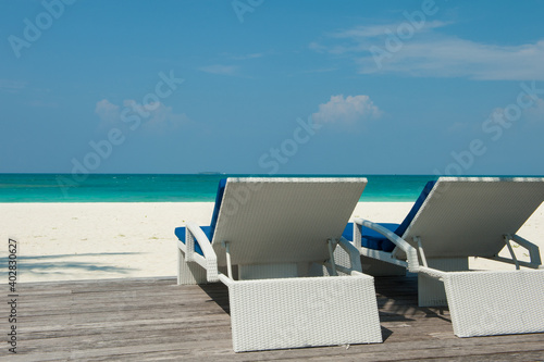  White sand beach and turquoise ocean palm leaves and modern white rattan furniture. Relaxing sea landscape