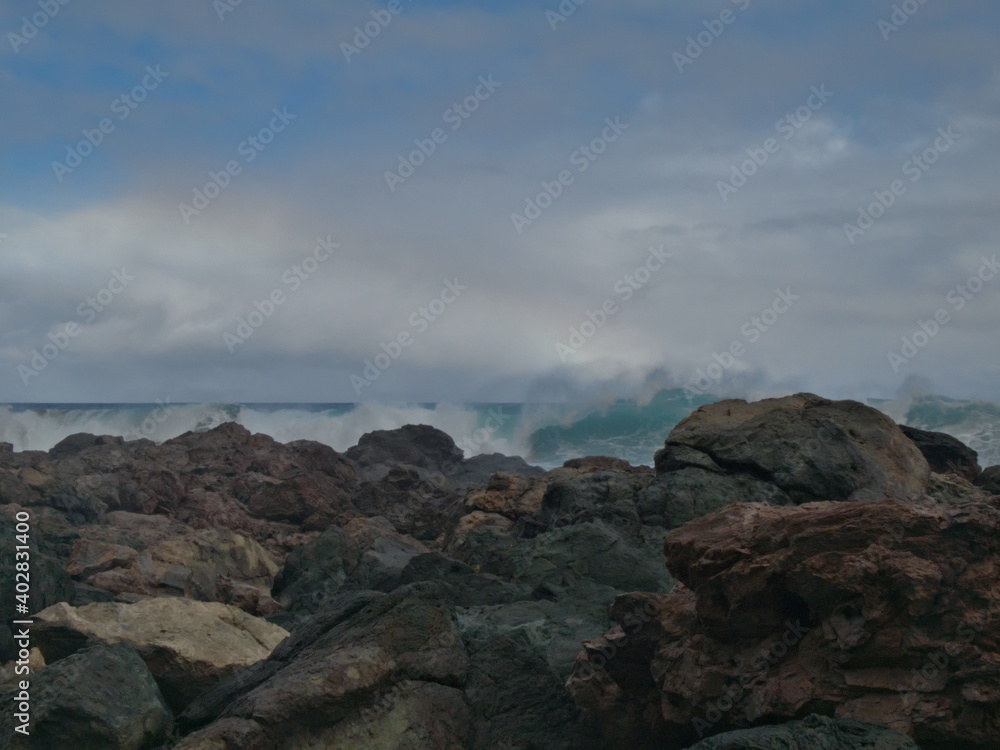 Waves crashing against the coast and with the rainbow in the background