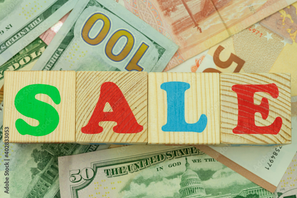 The inscription sale in multicolored cubes on the background of banknotes euro dollars rubles The inscription sale in multicolored cubes on the background of banknotes euro dollars rubles