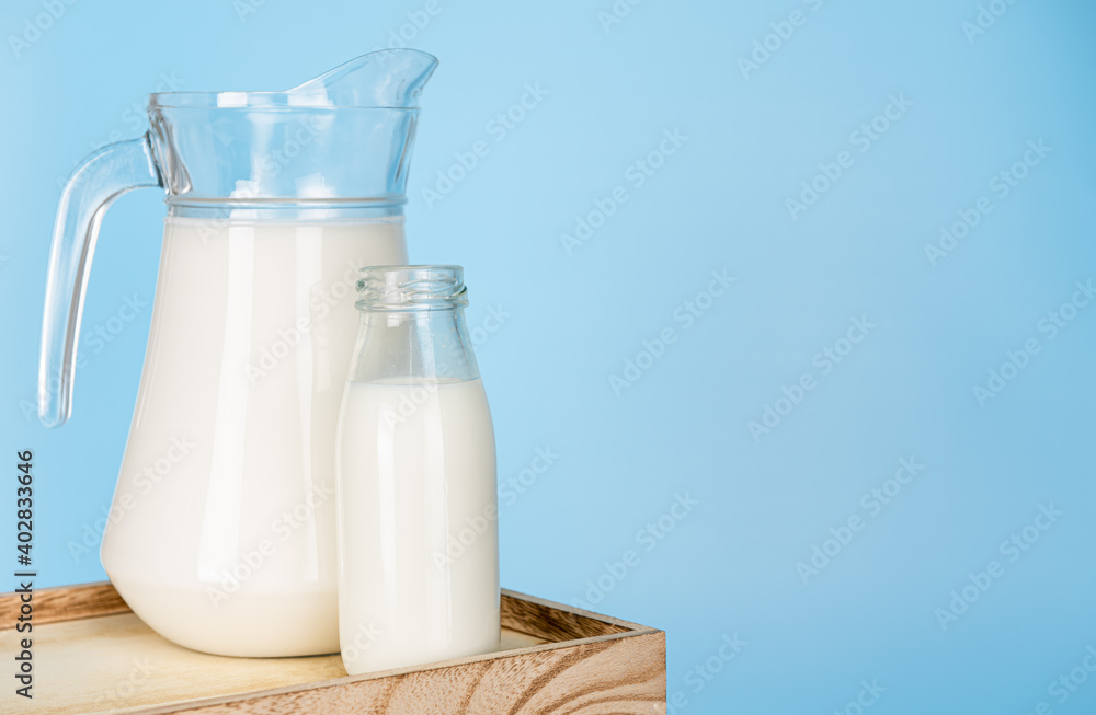 jug and bottle of fresh milk glass on wooden crate box on a blue background. Raw milk is high in calcium and protein to drink for all ages. Milk consumption nutritious and healthy dairy products. jug and bottle of fresh milk glass on wooden crate box on a blue background. Raw milk is high in calcium and protein to drink for all ages. Milk consumption nutritious and healthy dairy products.