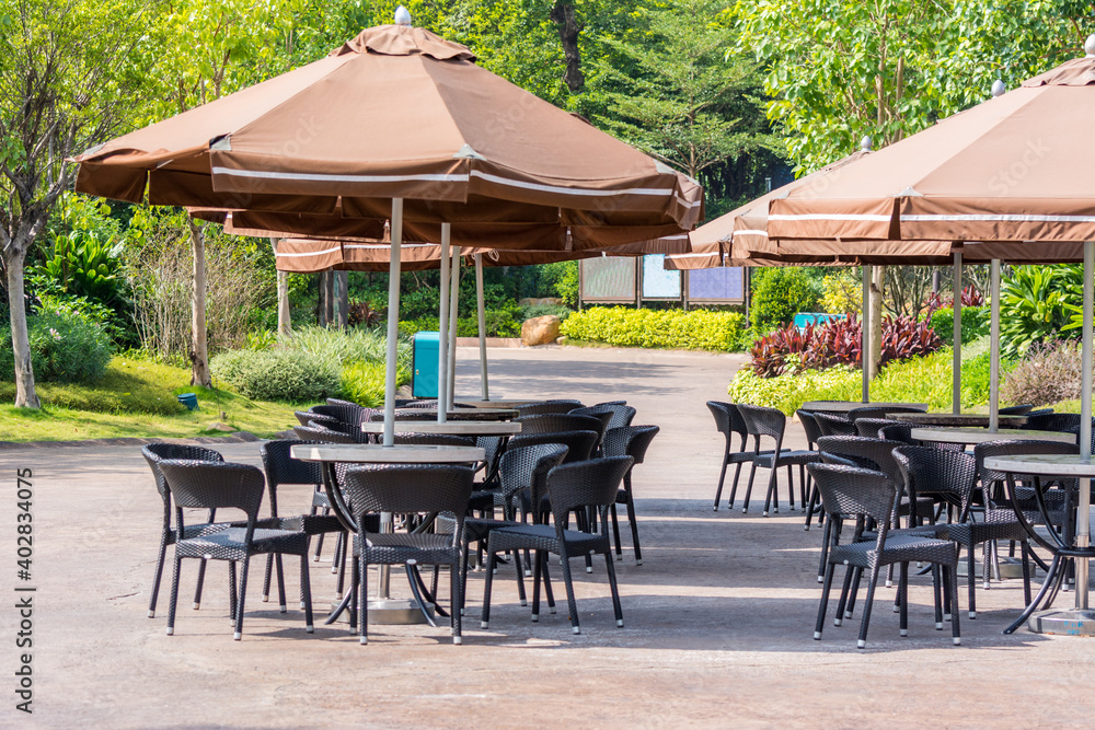 Outdoor black tables and chairs and brownish red big umbrellas
