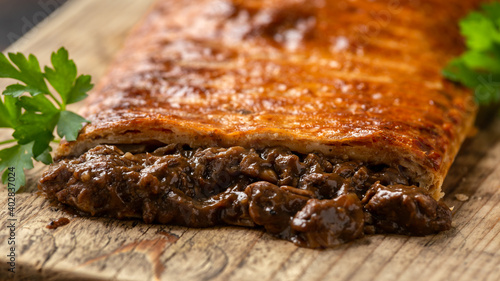 Steak and onion lattice pie on rustic wooden board
