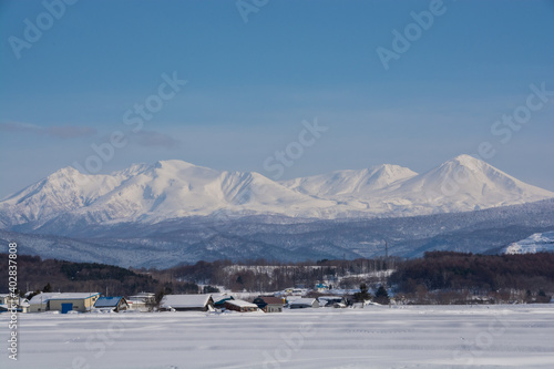 冬の晴れた日の農村地帯と雪山 大雪山