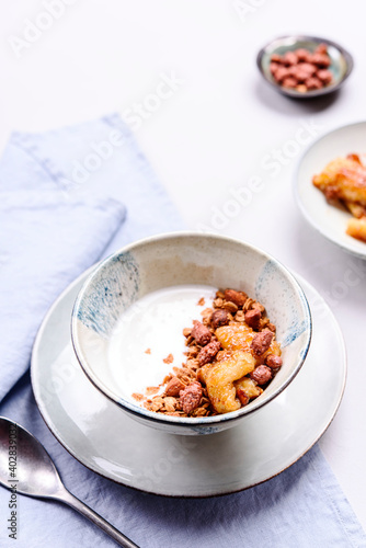 Healthy breakfast yogurt bowl with granola and caramelized bananas and nuts on grey concrete background. Selective focus