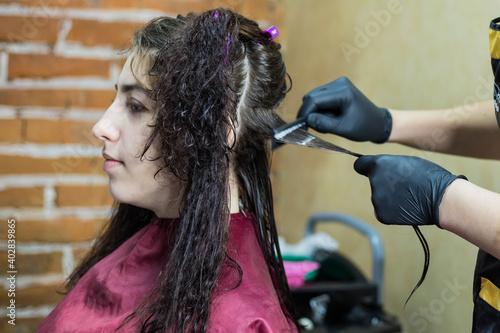 Brunette girl does keratin hair straightening on her curly hair. Keratin hair straightening in the salon.