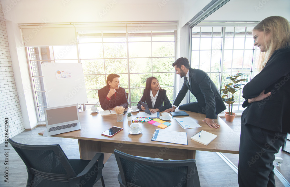 Smiling diverse colleagues brainstorm laugh at office meeting