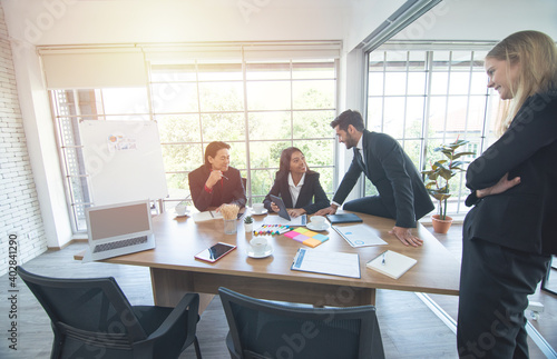 Smiling diverse colleagues brainstorm laugh at office meeting