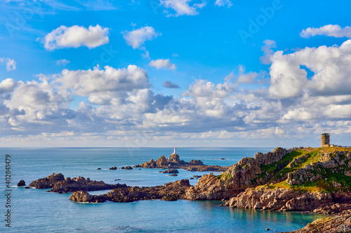 Image of corbiere lighthouse with WW2 tower, coastline and calm sea. Jersey, Channel Islands