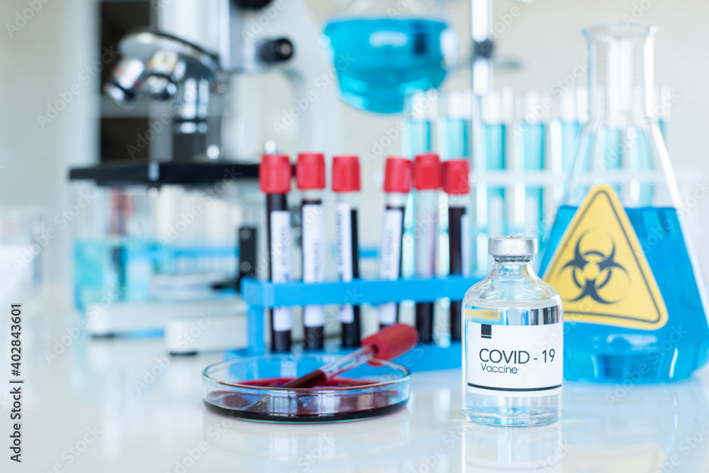 Coronavirus vaccine vials with group of chemical equipment in laboratory.