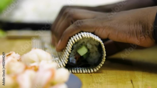 close up view of African American black hand preparing to roll fresh raw sushi Japanese style. The delicious healthy seafood is an Asian cultural dish recipe 