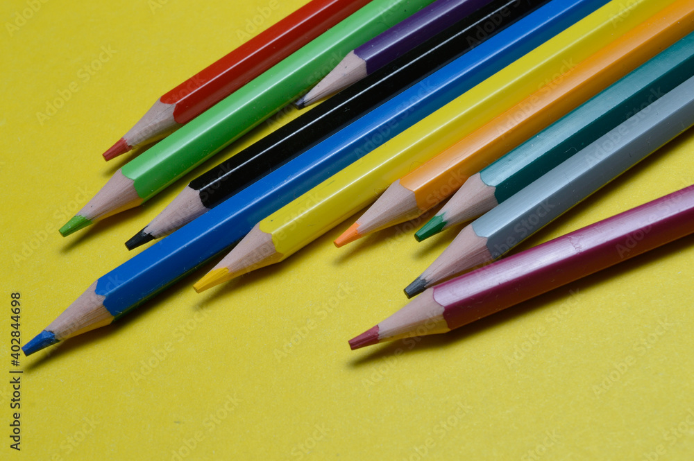 several multi-colored pencils lie on the yellow surface. several multi-colored pencils lie on the yellow surface.