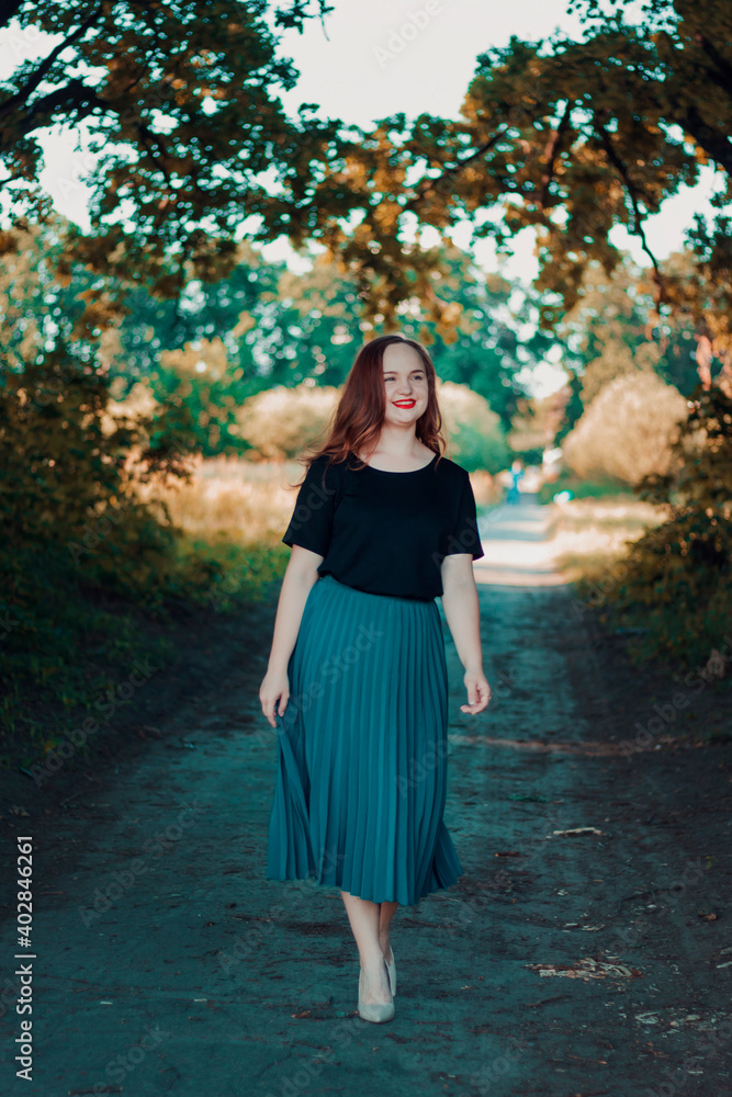 A beautiful, elegant girl in full growth. Walk in the park. Happy cute girl in a turquoise skirt and beige high heels. A beautiful, elegant girl in full growth. Walk in the park. Happy cute girl in a turquoise skirt and beige high heels.