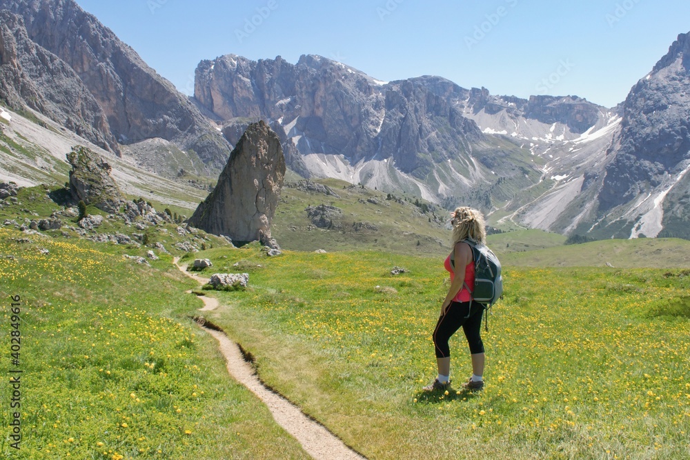 Woman hiker watching beautiful summer mountain scenery in Italian Dolomites .