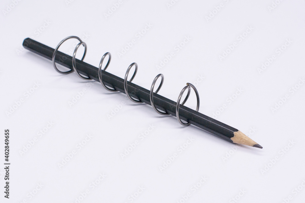 black pencil in a metal spiral on a white background black pencil in a metal spiral on a white background