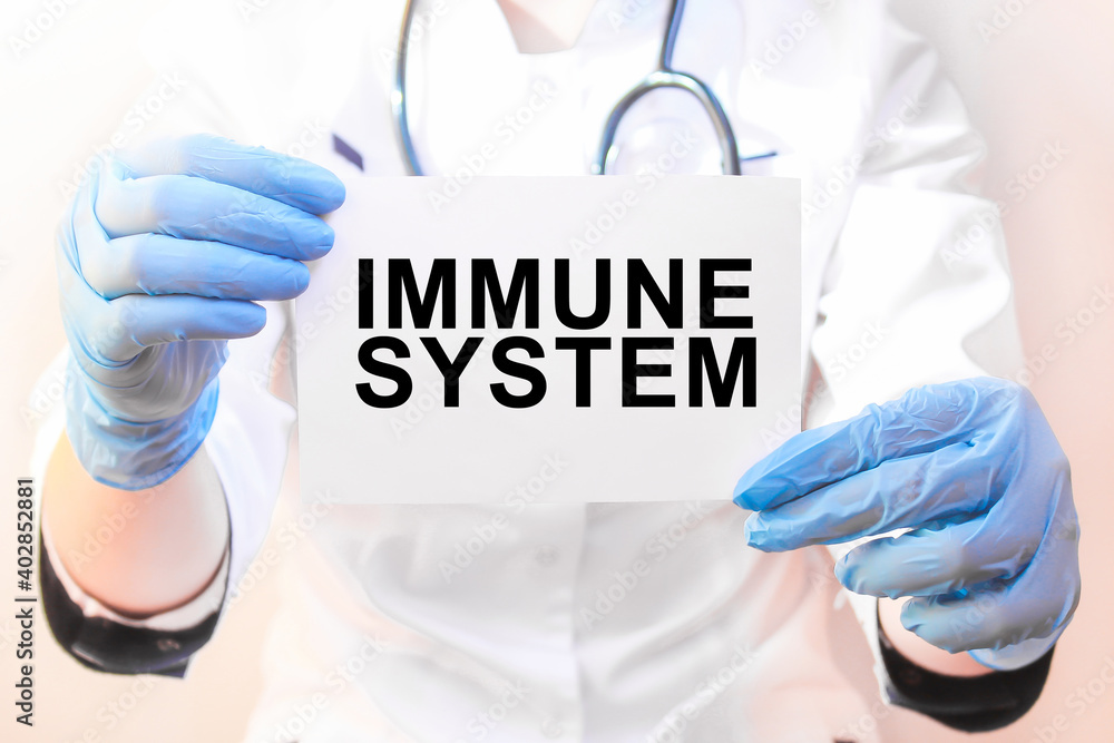 The doctor's blue - gloved hands show the word IMMUNE SYSTEM - . a gloved hand on a white background. Medical concept. the medicine The doctor's blue - gloved hands show the word IMMUNE SYSTEM - . a gloved hand on a white background. Medical concept. the medicine
