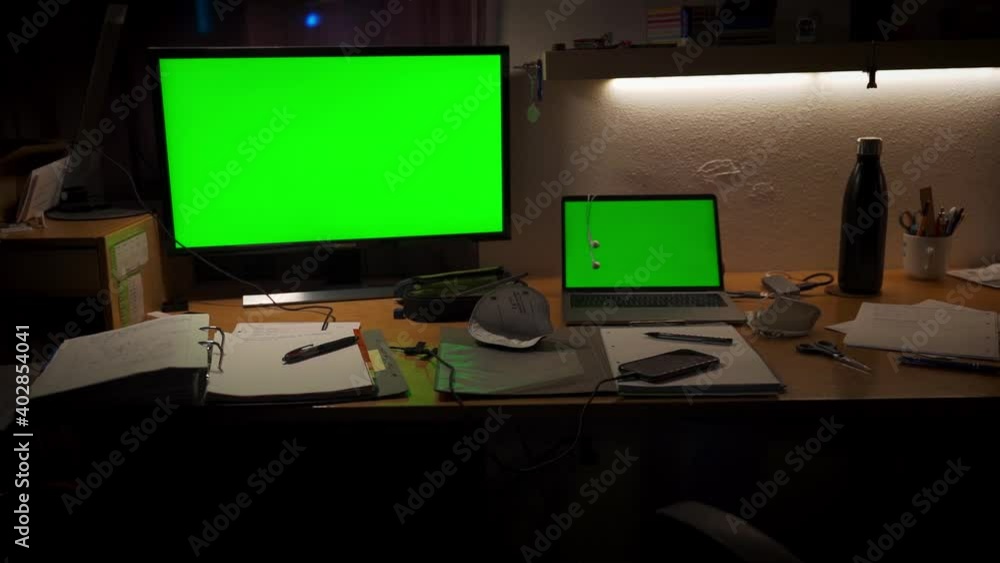 A messy desktop with a green-screen computer and display, a mask, stuff for study or school. A messy desktop with a green-screen computer and display, a mask, stuff for study or school.