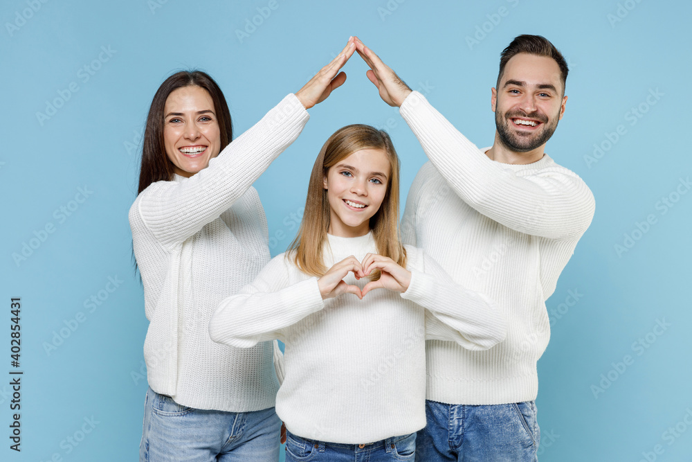 Funny parents mom dad with child kid daughter teen girl in sweaters hold hands above head roof of house showing shape heart isolated on blue background studio portrait. Family day parenthood concept. Funny parents mom dad with child kid daughter teen girl in sweaters hold hands above head roof of house showing shape heart isolated on blue background studio portrait. Family day parenthood concept.
