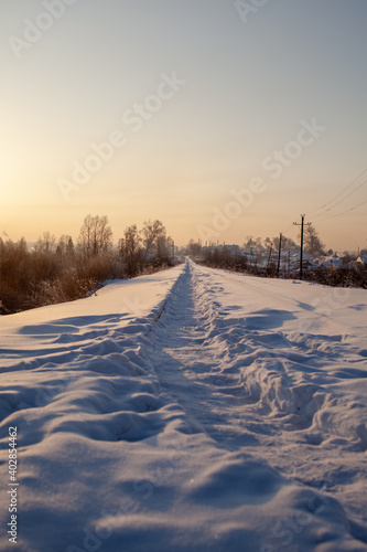 A snow-covered railway and a path trodden by people on it in winter.