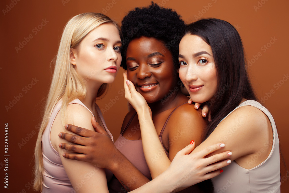 young pretty asian, caucasian, afro woman posing cheerful together on brown background, lifestyle diverse nationality people concept young pretty asian, caucasian, afro woman posing cheerful together on brown background, lifestyle diverse nationality people concept