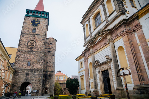 Old medieval stone gothic tower Valdice gate or Valdicka brana and baroque Church of St. James the Greater in autumn, Jicin, Bohemian Paradise region, Czech Republic photo