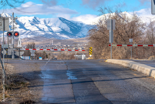 Road and railway intersection at level crossing with red lights signal and gates photo