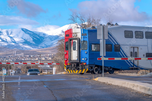 Obraz na plátně Train on railway and road intersection against snowy mountain and blue sky views