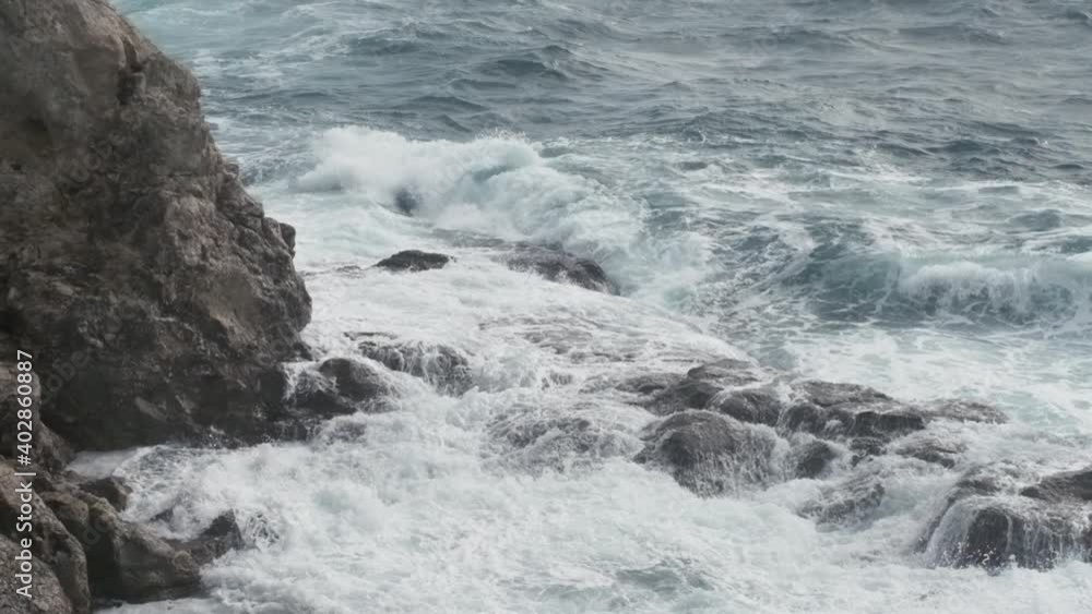 SLOW MOTION 240 FPS. Powerful ocean wave splashes across a big rock in the middle of the rough sea. SLOW MOTION 240 FPS. Powerful ocean wave splashes across a big rock in the middle of the rough sea.