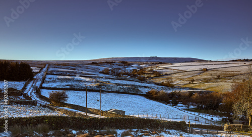 Snowy Nidderdale and late afternoon sun lights up moorland pastures, fields and a single track road.  © Fencewood studio