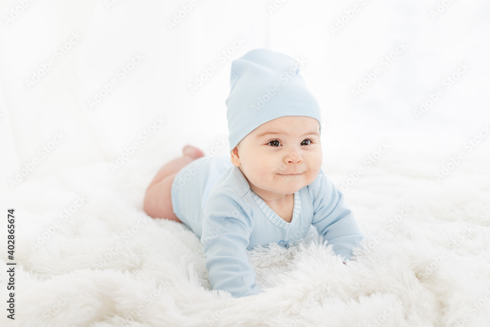 a baby in blue clothes is lying on his stomach on a white rug a baby in blue clothes is lying on his stomach on a white rug